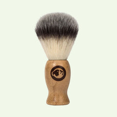 The Original Shave Brush features a light brown bamboo handle with an animal head logo and dense, soft bristles that fade from dark to white, ideal for achieving a traditional shaving experience.