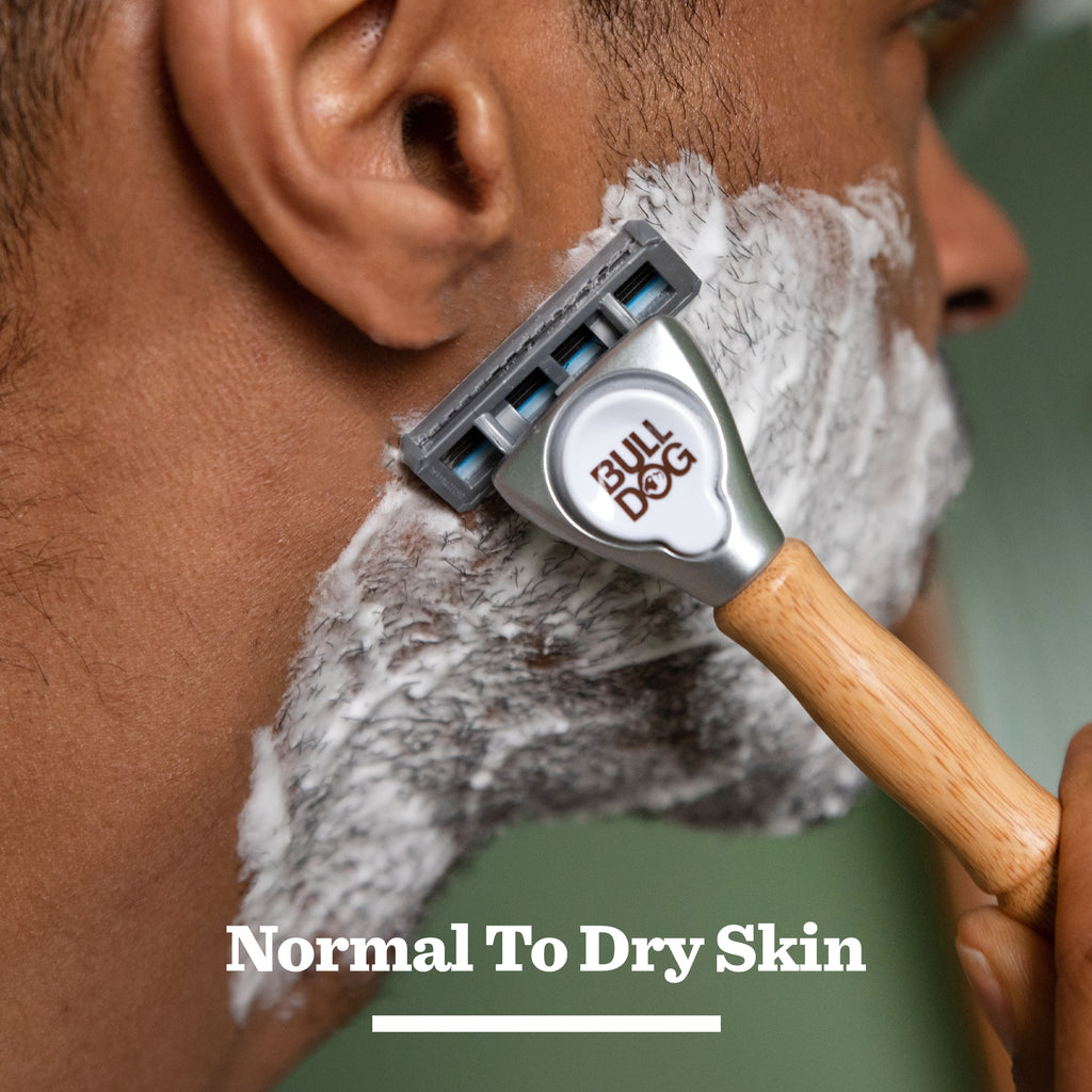 A close-up of a man shaving with a Bulldog razor and Original Foaming Shave Gel, his face covered in lather. The phrase Normal To Dry Skin appears at the bottom of the image.