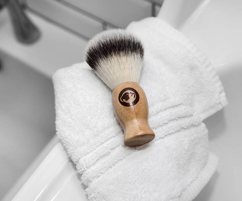 The Original Shave Brush rests on a folded white towel by the sink, ready for a classic shave in your bathroom.