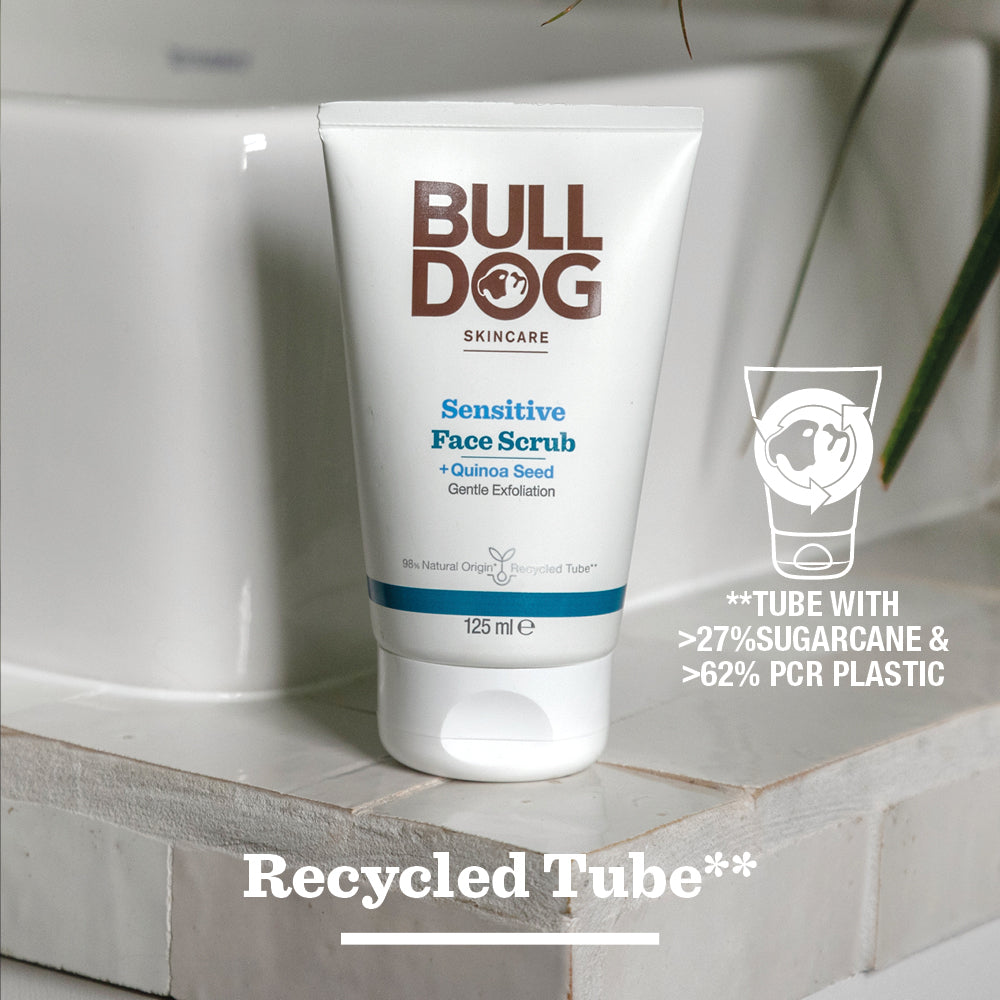 A tube of Sensitive Face Scrub sits on a bathroom countertop, highlighting natural origin ingredients, over 27% sugarcane content, and 62% post-consumer recycled plastic. “Recycled Tube” appears at the bottom.