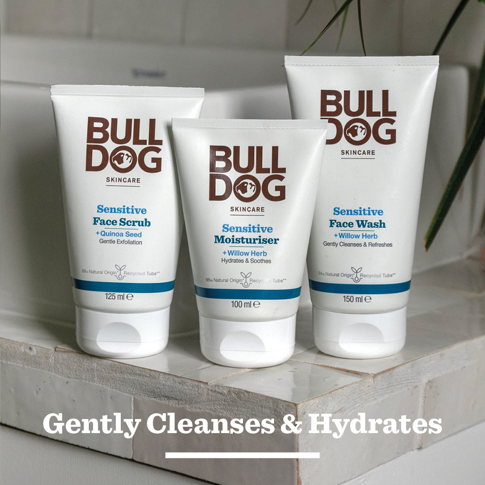 The Bulldog Sensitive Face Scrub for men, made with natural origin ingredients, is placed on a bathroom surface with the text Gently Cleanses & Hydrates displayed below.