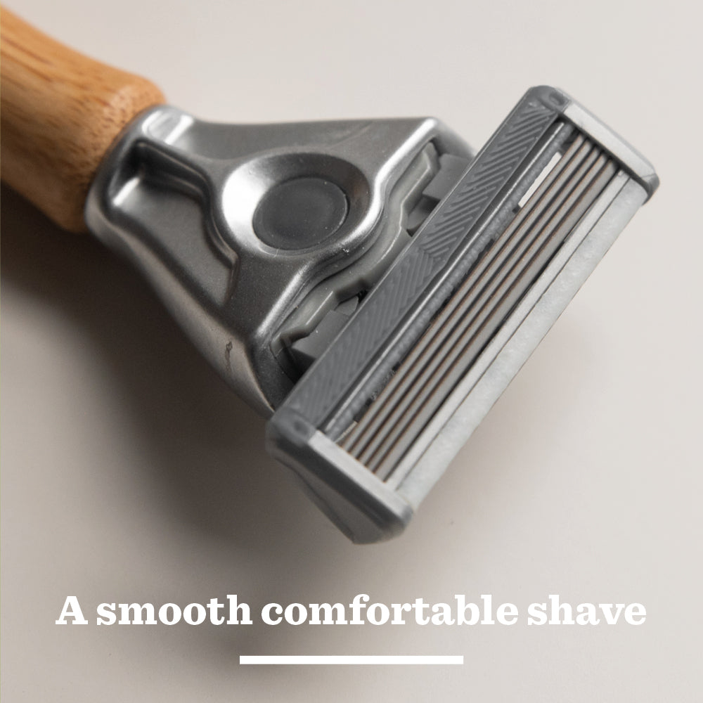 A close-up of the Original Steel Blades razor with a wooden handle and metal head, featuring tempered steel blades, rests on a light surface with the text “A smooth comfortable shave” below.