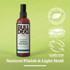 A bottle of Original Hair Styling Salt Spray stands on a green background, displaying icons for naturally derived ingredients, vegan approval, and cruelty-free. Text reads: Natural Finish & Light Hold with Mediterranean sea salt.
