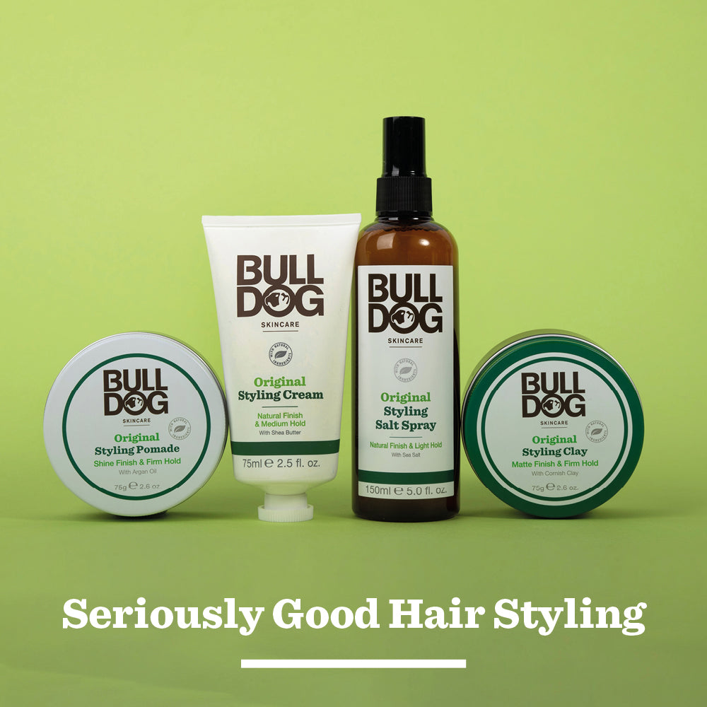 Four Bulldog Skincare hair styling products—including the Original Hair Styling Salt Spray—are arranged in a row against a green background. Text below reads, “Seriously Good Hair Styling with naturally derived ingredients.”.