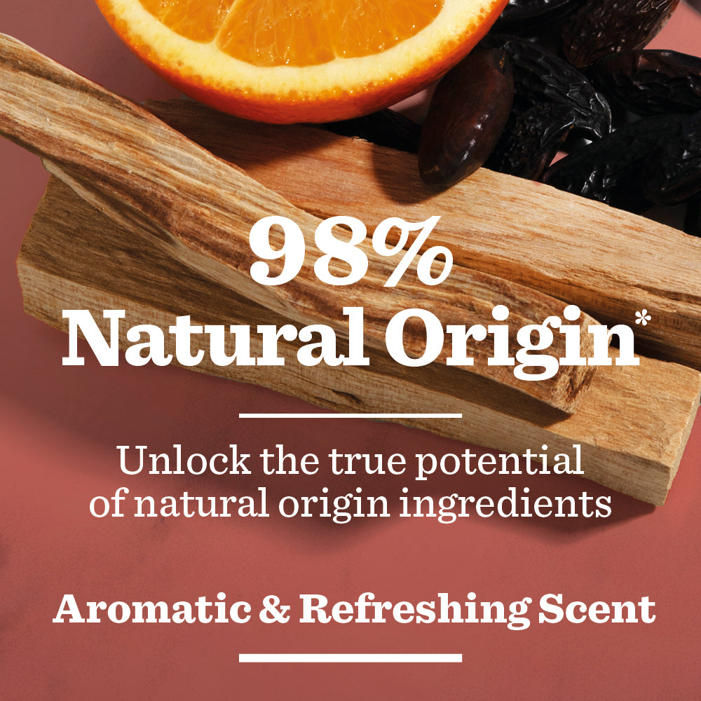 A slice of orange, dried vanilla pods, and wooden sticks on a red surface with the text: 98% Natural Origin* Bergamot & Sandalwood Spray Deodorant—vegan formula with an aromatic, refreshing scent.