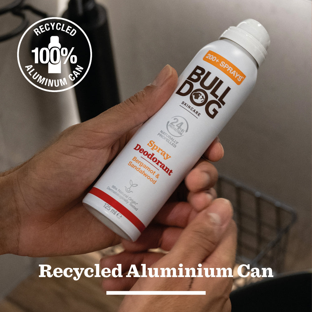 A person holds a Bergamot & Sandalwood Spray Deodorant can, showing it’s made from 100% recycled aluminum and crafted with natural ingredients.