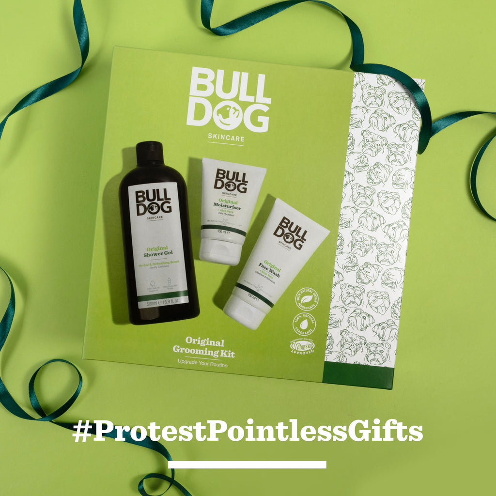 The Original Grooming Kit from Bulldog Skincare, including the Original Moisturiser and two essentials, is shown on a green background with ribbon. At the bottom, the text reads: #ProtestPointlessGifts.