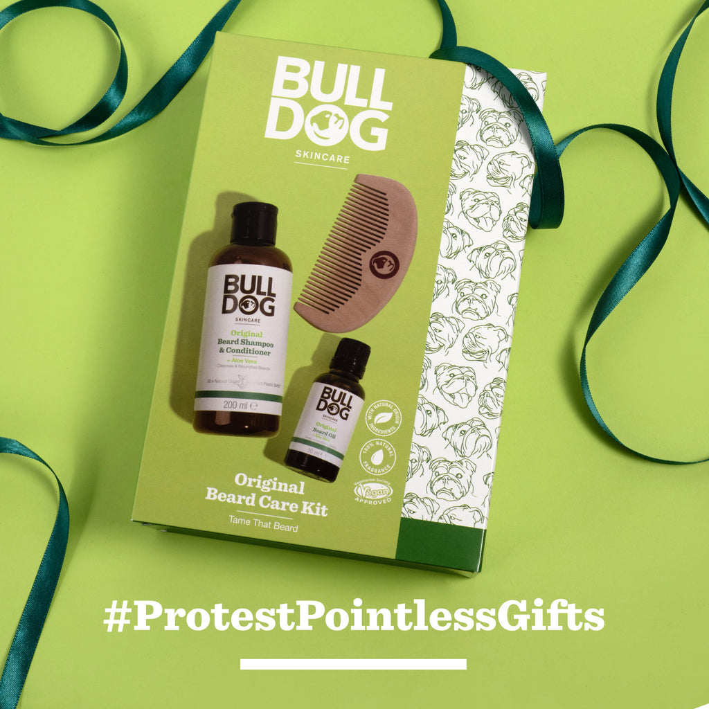 A green box of the Original Beard Care Kit, with beard shampoo & conditioner, beard oil, and a comb, rests on a green background with ribbon. #ProtestPointlessGifts appears in white text at the bottom.
