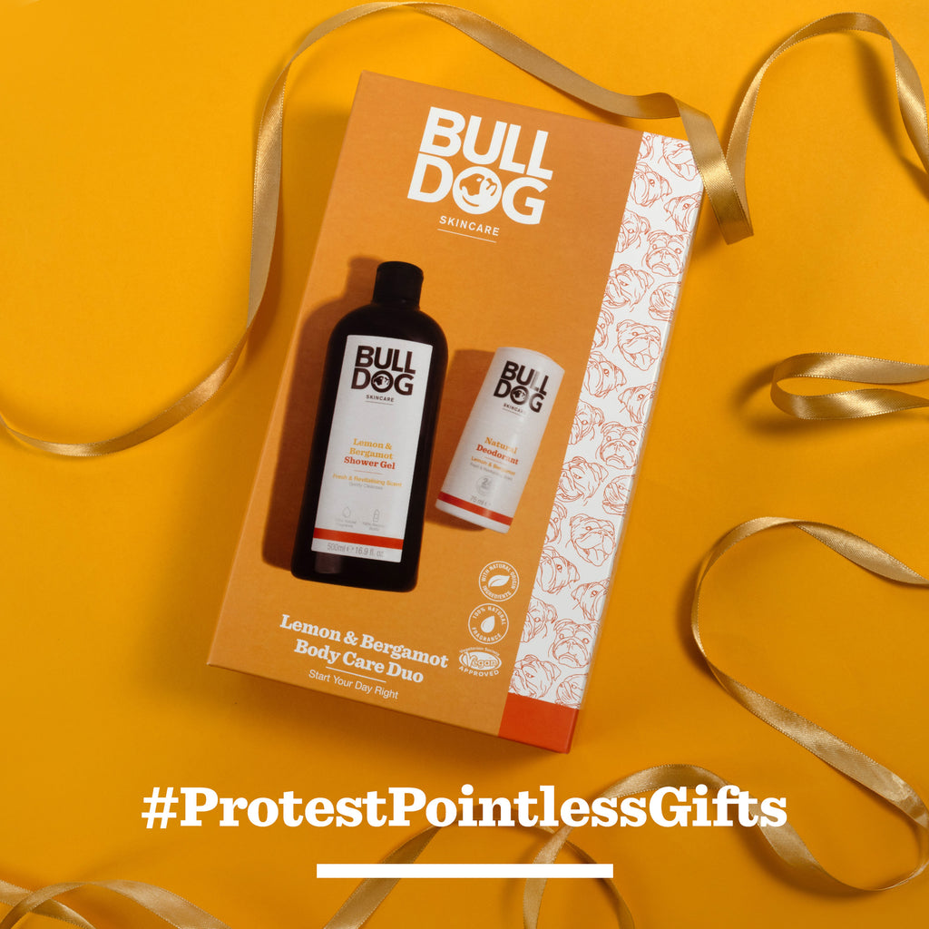 Lemon & Bergamot Body Care Duo gift box—includes shower gel—shown on an orange background with a gold ribbon. White text reads #ProtestPointlessGifts, making it a thoughtful gift for men.