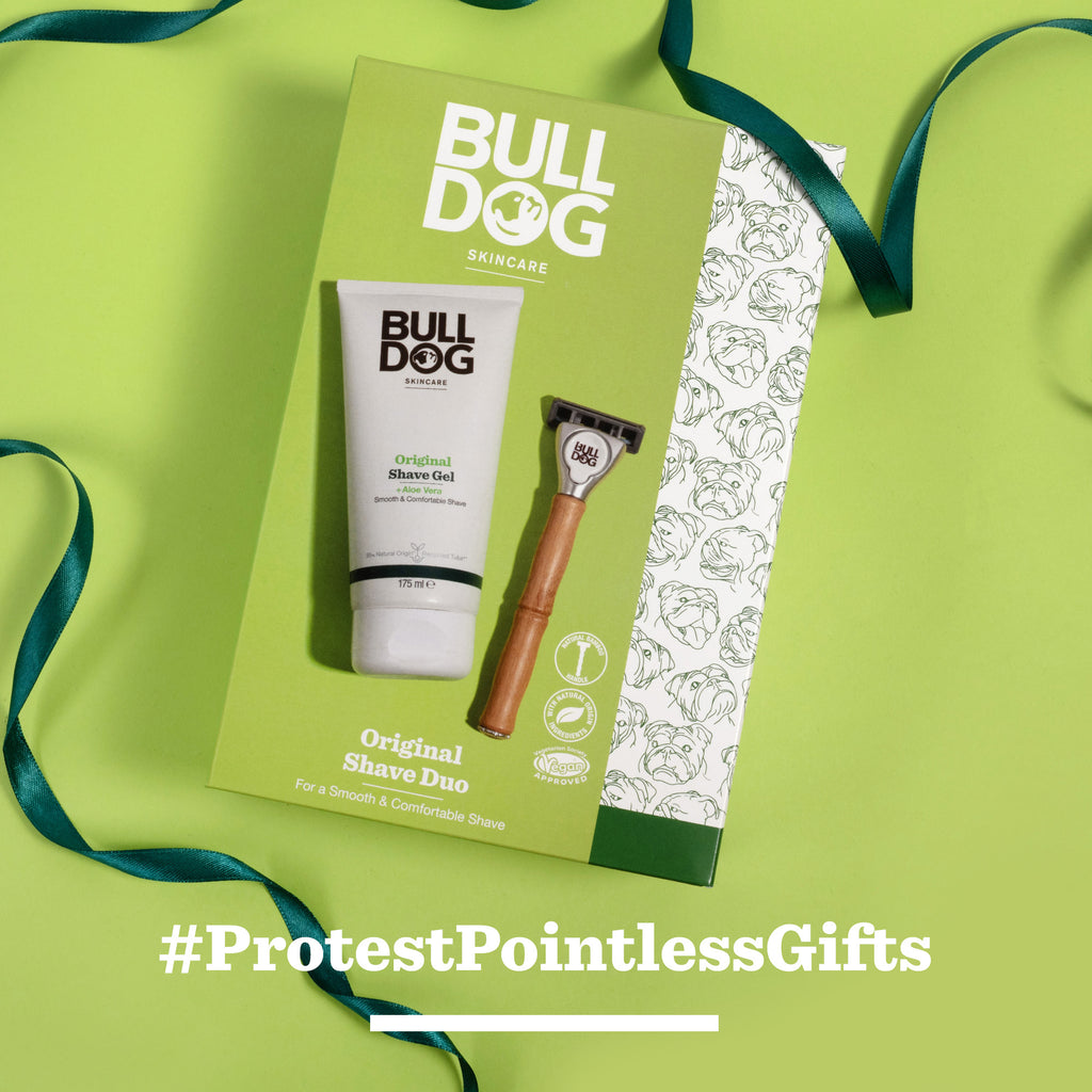 The Original Shave Duo, featuring shave gel and a bamboo razor with bulldog face illustrations, sits on a green background with a dark green ribbon. Text reads #ProtestPointlessGifts.