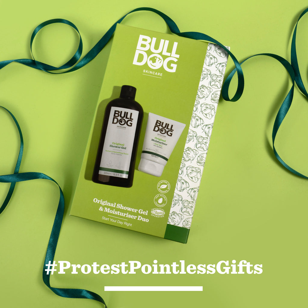 The Body Care Duo by Bulldog Skincare—featuring shower gel and Original Moisturiser—is shown on a yellow background with a green ribbon. Ideal for men’s gifting, it features the #ProtestPointlessGifts message at the bottom.